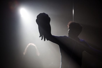  A silhouette of Charlie (Sam Swann) holding the C'thulu prosthetic mask out into the bright back white backlight. 