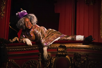 Mrs Aphrodite (Tameka Empson) hanging out of the royal box in the theatre.