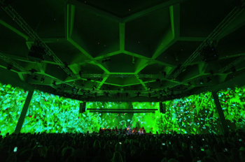 A wide angle shot of the congress hall stage and ceiling, with full width video projection of AI generated nature images created by Refik Anadol.