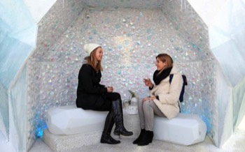  Two people sit inside the iridescent crystal grotto wrapped up in coats. 